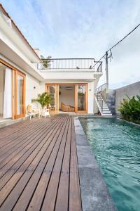 ein Haus mit einer Holzterrasse und einem Pool in der Unterkunft Diana ArtVilla by ArthouseBali in Canggu