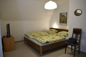 um quarto com uma cama, uma televisão e uma cadeira em Haus Holländerdeich em Dagebüll