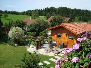 a small wooden cabin in a yard with flowers at Ferienwohnungen Krenn in Tittling