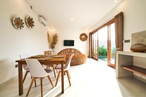 ein Esszimmer mit einem Holztisch und weißen Stühlen in der Unterkunft Diana ArtVilla by ArthouseBali in Canggu