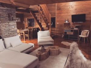 a living room with white couches and a tv at Zlatibor Sky Inn in Zlatibor