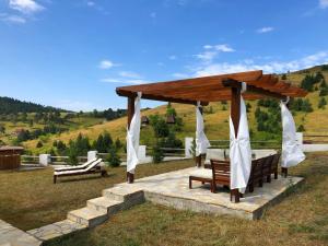 un cenador con mesa y bancos en un campo en Zlatibor Sky Inn, en Zlatibor