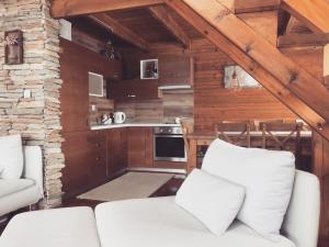 a living room with two white chairs and a kitchen at Zlatibor Sky Inn in Zlatibor