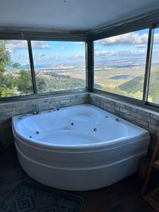 a large white bath tub in a room with windows at Panoramic View in ‘Isfiyā