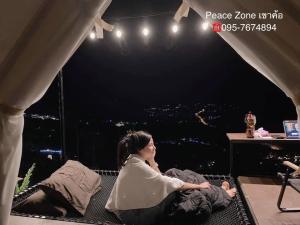 Eine Frau, die auf einer Bühne auf einem Bett liegt. in der Unterkunft Peace Zone เขาค้อ in Khao Kho