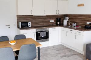 a kitchen with white cabinets and a wooden table at Ferienwohnung Tide 21 in Norddeich