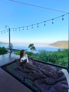 a woman laying on a bed on a balcony at Peace Zone เขาค้อ in Khao Kho