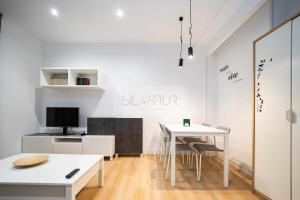 a white room with a desk and a table with chairs at Asturches Apartamento in Gijón