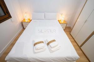 a bedroom with a white bed with two towels at Asturches Apartamento in Gijón