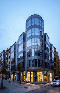 a large glass building with people walking in front of it at Asturches Apartamento in Gijón