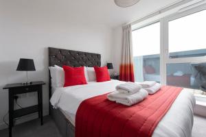 a bedroom with a large bed with red pillows at Finsbury Park Penthouse: Luxe City Living in London
