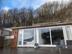 a patio with a balcony on top of a house at May View - Luxury Sea View Apartment - Millendreath, Looe in Looe