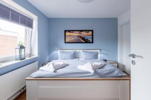 a bedroom with a bed with a blue wall at Haus Bendix in Dagebüll