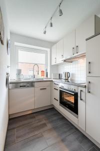 a kitchen with white cabinets and a sink and an oven at Haus Bendix in Dagebüll