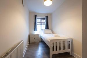um pequeno quarto com uma cama e uma janela em Comfy - 3 Bedroom Flat With Parking em Southampton