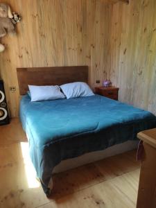 a bedroom with a bed with a wooden wall at cabaña de 2 pisos in Coñaripe