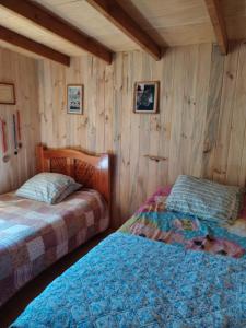 two beds in a room with wooden walls at cabaña de 2 pisos in Coñaripe