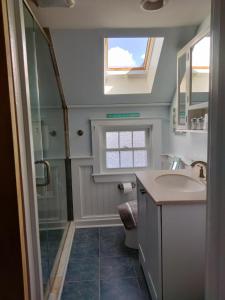 a bathroom with a sink and a shower and a window at Sandtrap Cape Cod in West Yarmouth