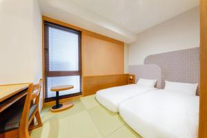 a bedroom with two beds and a desk and a window at Hop Inn Kyoto Shijo Omiya in Kyoto