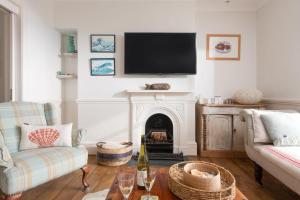 a living room with a fireplace and a flat screen tv at La Folie, Fowey in Fowey