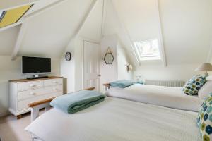 a bedroom with two beds and a tv on a dresser at La Folie, Fowey in Fowey