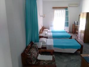 Habitación con 4 camas, silla y ventana en Damias Village, en Parikia