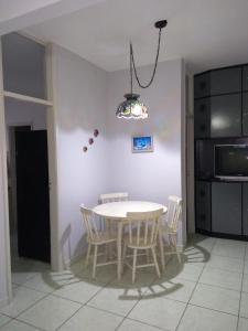 a table and chairs in a kitchen with a chandelier at Pé na areia in Mongaguá