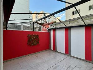 Habitación con una pared de color rojo y blanco y una ventana en Experiencia Aguirre a dos cuadras del subte B. Corazon de outlets, comercios y bares gastronomicos. en Buenos Aires