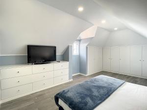 a white bedroom with a tv on a dresser at Casa da Horta by Atlantic Holiday in Santa Cruz