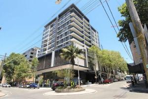 a tall building with a palm tree in front of it at Cozy Apartment at St Leonard in Sydney