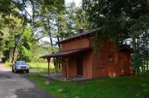 a wooden cabin with a car parked in front of it at Chata Česká Kubice in Česká Kubice