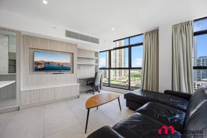 a living room with a couch and a tv at MetaWise Sydney CBD Haymarket Luxe 2Bed Penthouse Aqua in Sydney