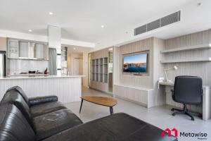 a living room with a leather couch and a television at MetaWise Sydney CBD Haymarket Luxe 2Bed Penthouse Aqua in Sydney