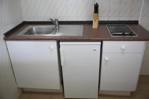 a kitchen with white cabinets and a sink at Apartamentos Mar y Sal in La Savina