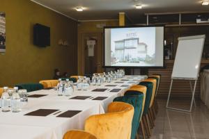 una sala de conferencias con mesas y sillas largas y una pantalla en Euro Garni Hotel en Belgrado