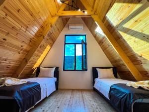 two beds in a attic room with a window at Qafqaz Royal Chalet in Gabala