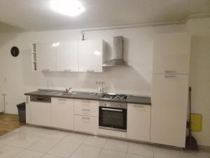 uma cozinha com armários brancos e um forno com placa de fogão em Apartman Sesvete em Sesvete