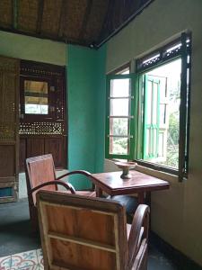 a room with a table and chairs and a window at duegoal farmhouse in Jatiluwih