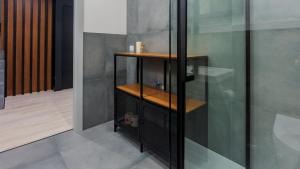 La salle de bains est pourvue d'une douche et d'une étagère en bois. dans l'établissement VacationClub - Ogrody Pieniawskie Apartament 48, à Polanica-Zdrój