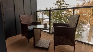 a balcony with two chairs and a table and a window at VacationClub - Ogrody Pieniawskie Apartament 48 in Polanica-Zdrój