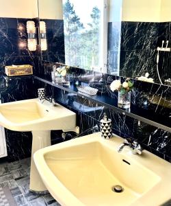 a black tiled bathroom with a sink and a mirror at Villa Billerud in Säffle