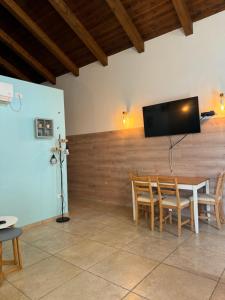 a dining room with a table and a flat screen tv at Cottage in Center of Historic Zichron Yaakov in Zikhron Ya‘aqov