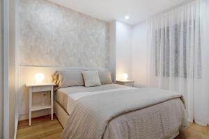 a white bedroom with a bed and two night stands at Magnolia's Las Canteras in Las Palmas de Gran Canaria