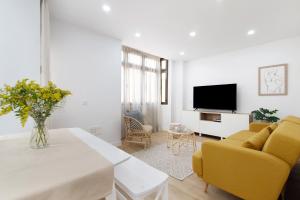 a living room with a table and yellow chairs at Magnolia's Las Canteras in Las Palmas de Gran Canaria
