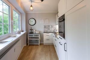 a kitchen with white cabinets and a clock on the wall at Ferienwohnung Bibi Bocksberg Hahnenklee in Goslar
