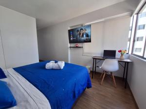 Habitacion baño Propio La Paz 1 في ليما: غرفة نوم مع سرير أزرق ومكتب مع الكمبيوتر المحمول