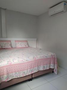 1 dormitorio con cama rosa y colcha rosa en Kitnet ótima localização em Garanhuns (103), en Garanhuns