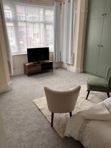 a hotel room with a bed and a television and a chair at Luxury Cosy Retreat Apt in London