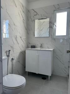 a white bathroom with a toilet and a sink at Duplex Marina de Vilamoura in Vilamoura