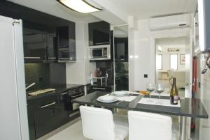 a kitchen with a black counter and white chairs at Porto Sea Apartments in Matosinhos